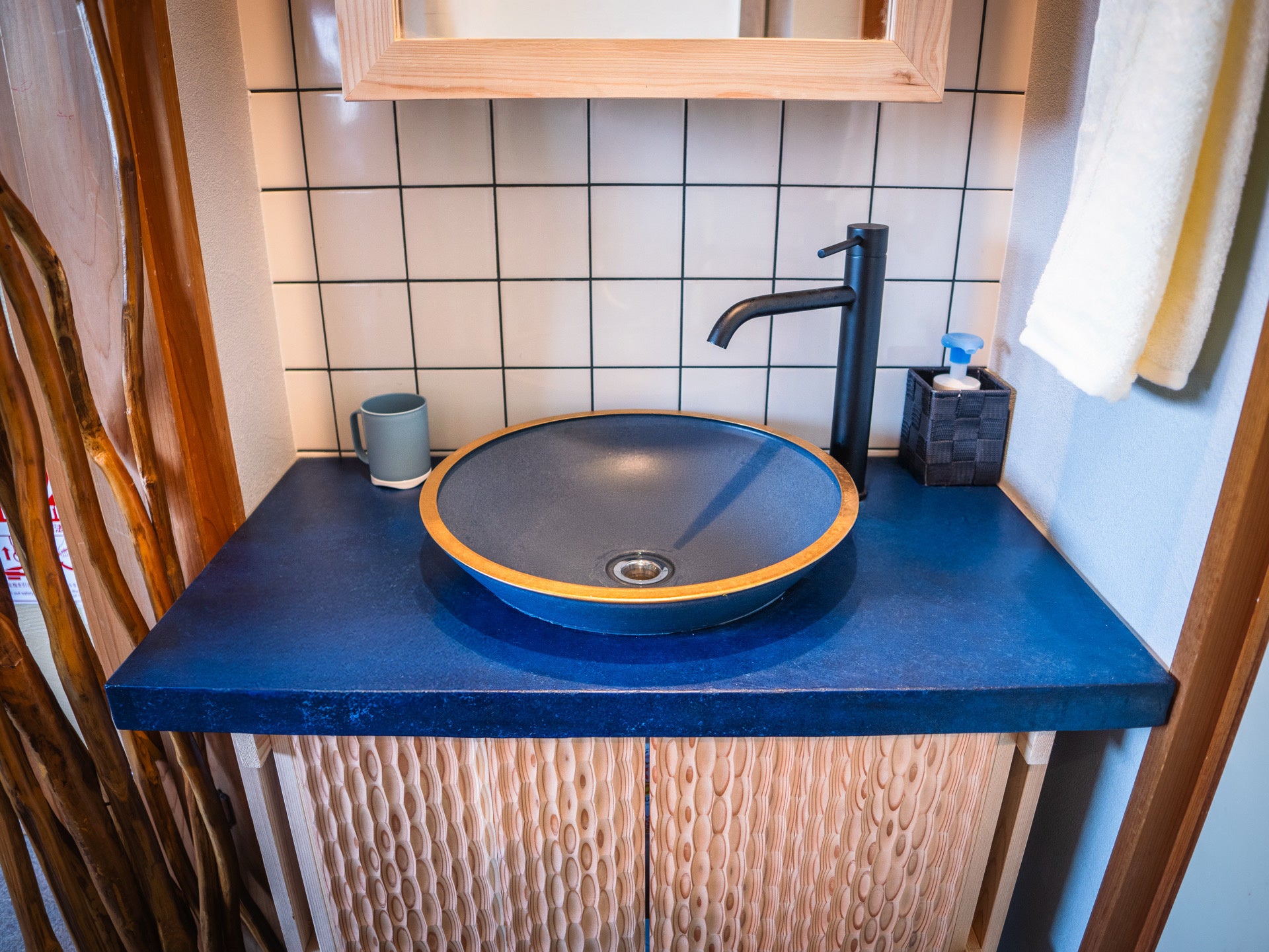 Washbasin, vanity, and doors featuring Otani-yaki pottery, indigo concrete, and wave panels