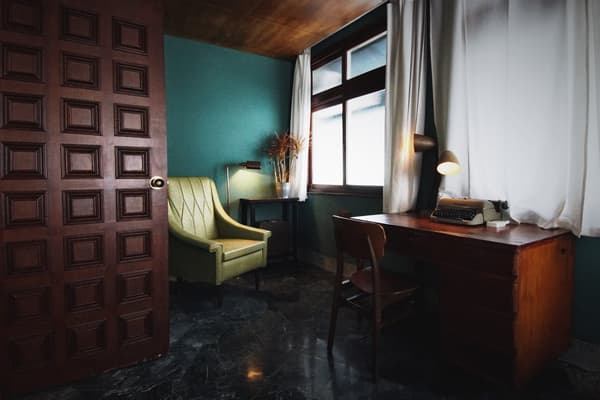 A room with a green wall and a vintage armchair at PARIPARI apt.