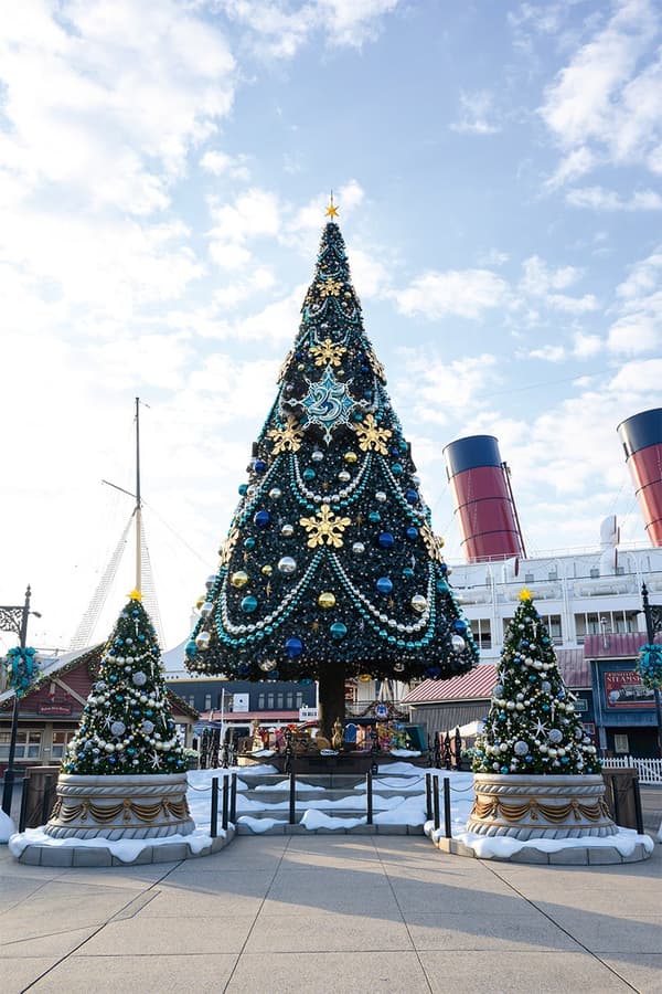 Pohon Natal besar yang dihias dengan ornamen biru dan logo peringatan ke-25 di American Waterfront