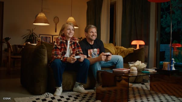 A parent and child playing the game together on a sofa