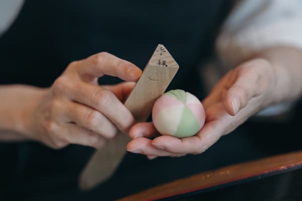Hands shaping a nerikiri with a wooden tool