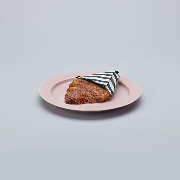 Krunji, un croissant aplanado y caramelizado, en un plato rosa