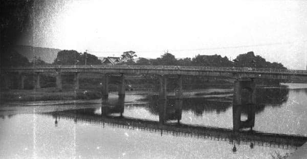 A historic black-and-white photograph of a bridge over a river
