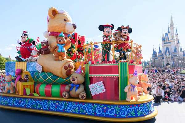 Mickey Mouse dan Minnie Mouse menaiki kendaraan hias parade Natal di depan Cinderella Castle