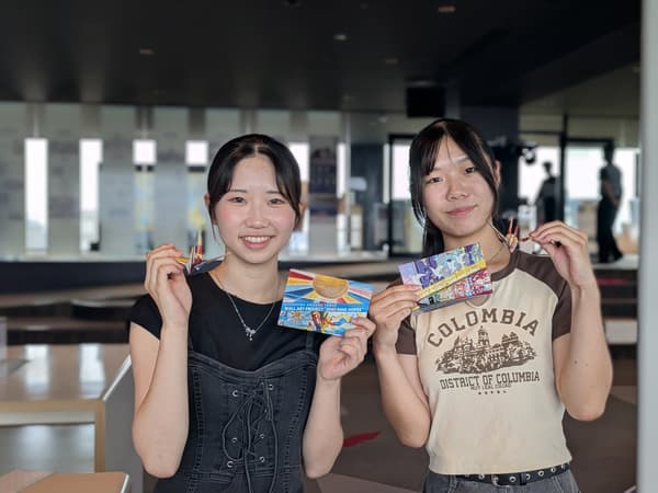 Visitors holding postcards and origami cranes at Orizuru Tower