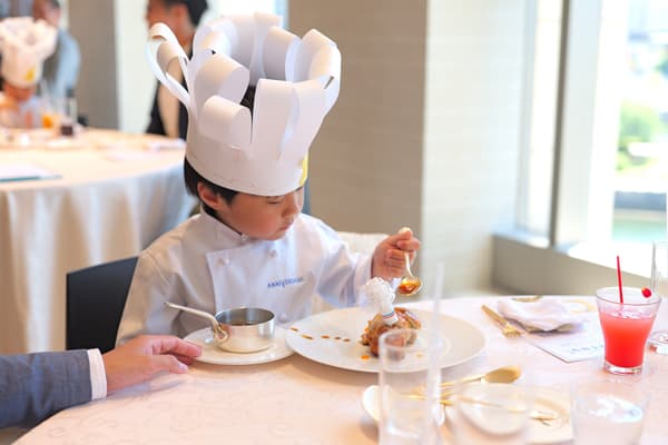 穿著廚師制服的孩子們為肉類料理添加醬汁