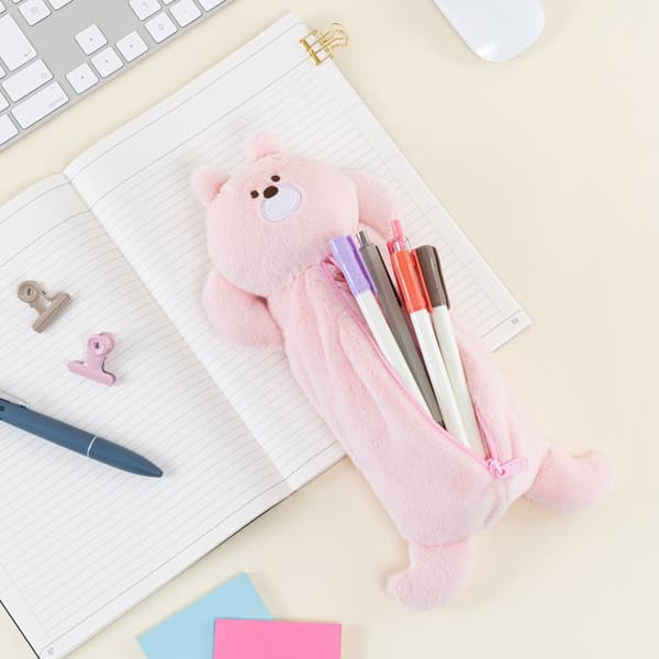 Estuche para lápices de conejo sosteniendo bolígrafos, descansando sobre un cuaderno