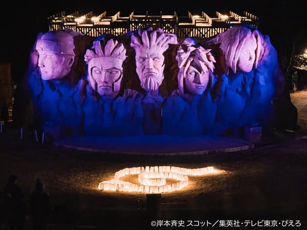 Hokage Rock diterangi di malam hari dengan simbol Konoha yang dibentuk dari lampion di depannya