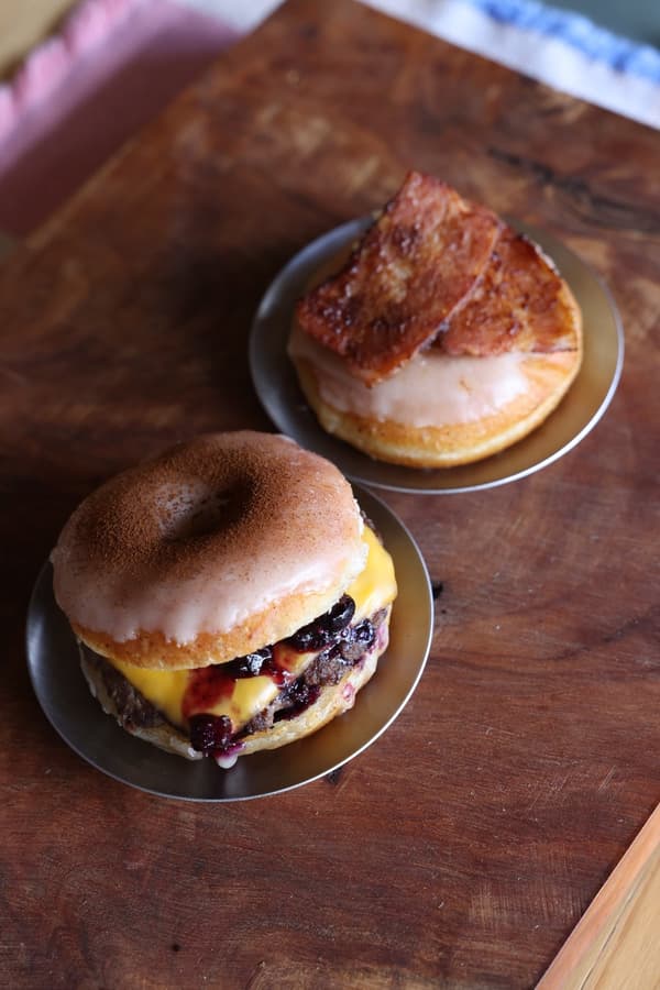 Una rosquilla cubierta con tocino y una hamburguesa de rosquilla con queso y salsa de bayas