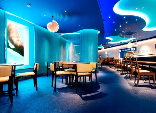 Interior restoran dengan pencahayaan biru dan kursi kayu
