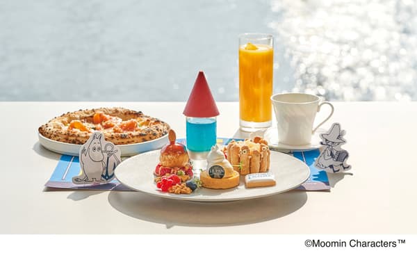 Pizza y postres temáticos de Moomin servidos en una mesa junto al mar