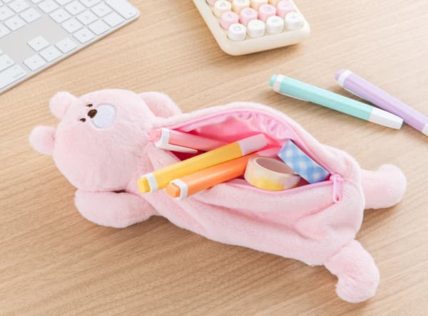 Estuche para lápices de conejo rosa con la cremallera abierta, conteniendo bolígrafos y cinta washi, descansando sobre un escritorio