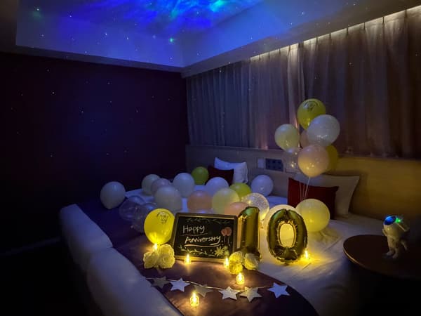 Kamar yang didekorasi untuk perayaan di malam hari, dengan bintang-bintang yang diproyeksikan di langit-langit