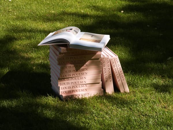 Tumpukan buku merek Louis Poulsen di atas halaman rumput