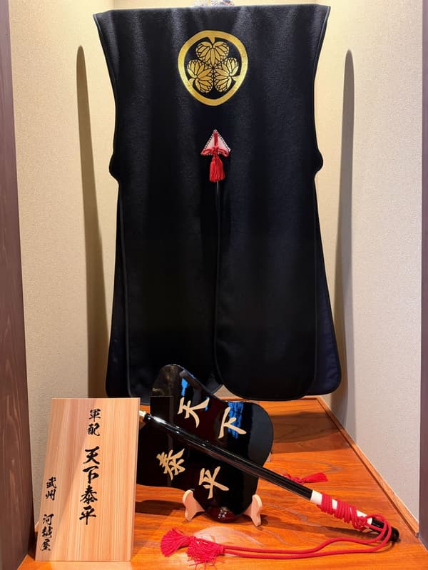 A jinbaori (samurai surcoat) associated with Lord Ieyasu, paired with a war fan.