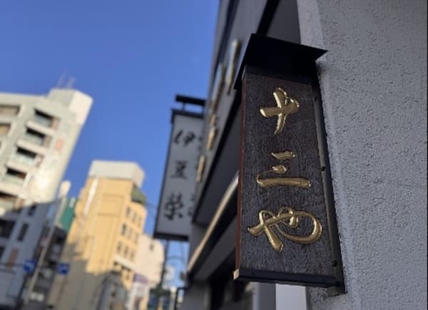 Letreros de tiendas de larga trayectoria en el distrito de Shinobazu, incluyendo Izuei Honten y Jusan-ya