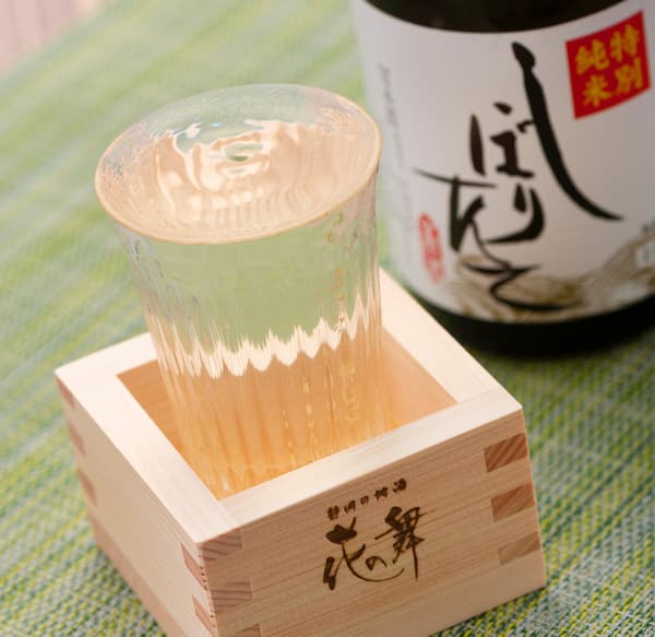 放入木製枡杯中的一杯花の舞新酒,旁邊有一瓶該款清酒