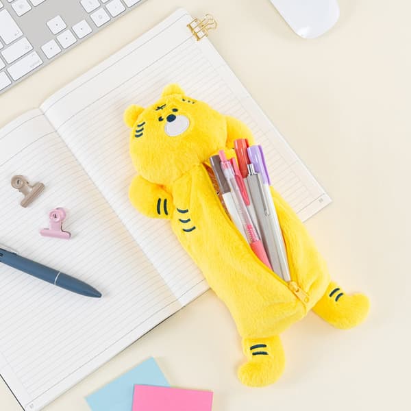 Estuche para lápices de tigre sosteniendo bolígrafos, descansando sobre un cuaderno