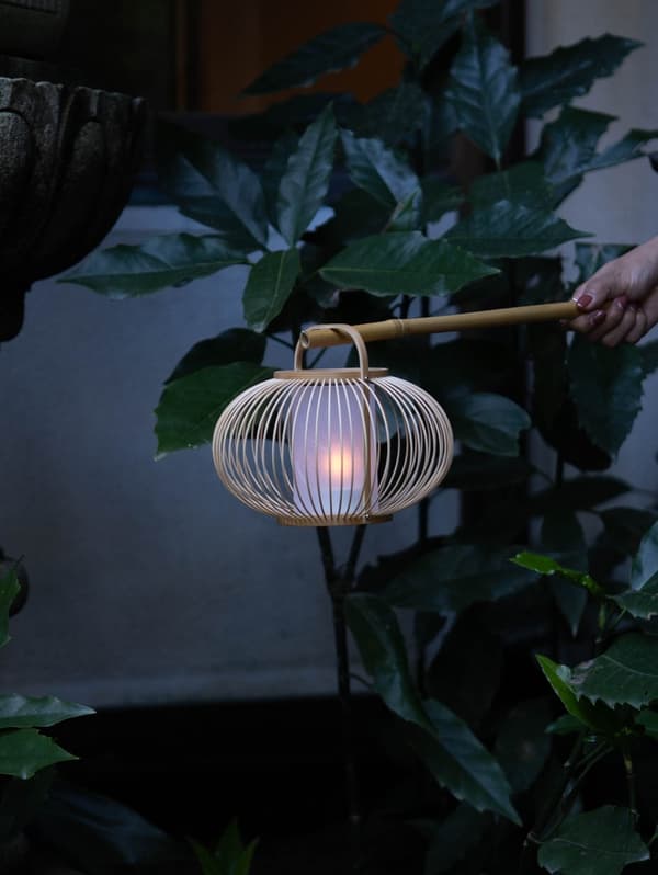 Una linterna bonbori chochin brillando junto a plantas