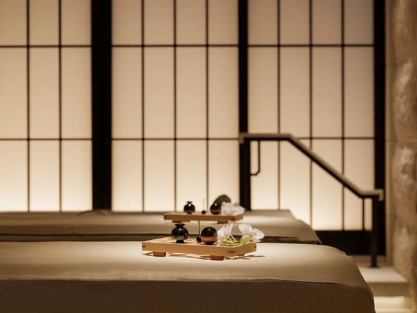 Tempat tidur perawatan dan layar bergaya shoji yang bercahaya lembut di spa