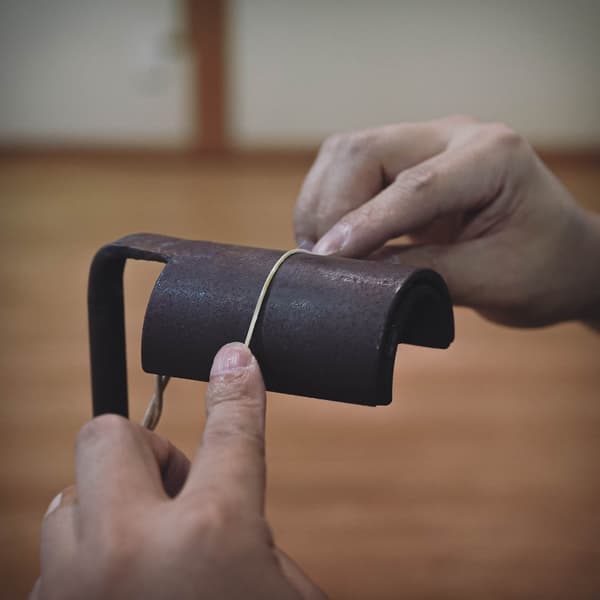 Manos trabajando el bambú con una herramienta en un taller