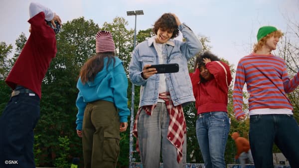 Friends playing Nintendo Switch 2 in handheld mode at a park