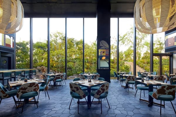 Dining room at KŌSA with floor-to-ceiling windows overlooking greenery