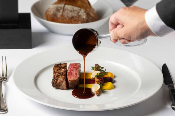 Beef dish with sauce being poured at New York Grill