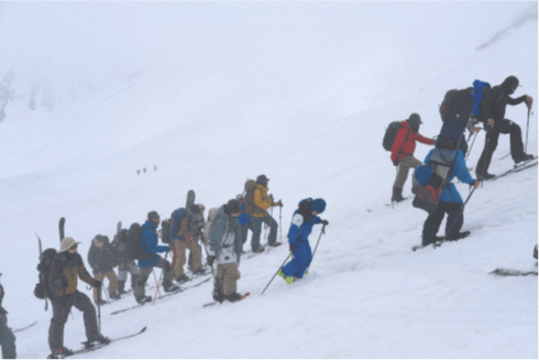 Participants ascending a snowy mountain led by a guide