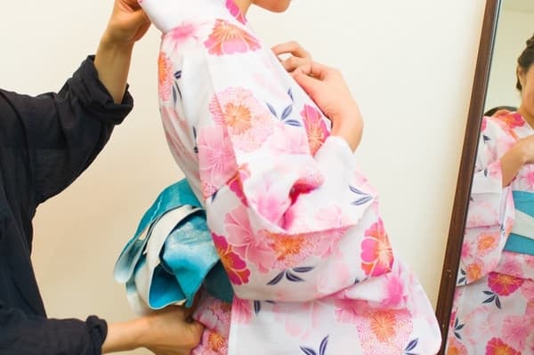 A professional dresser quickly and neatly helps guests into their yukata