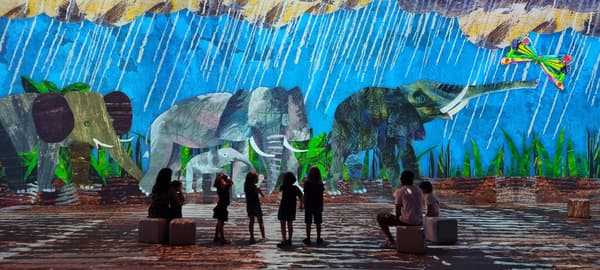Visitantes frente a elefantes proyectados bajo la lluvia