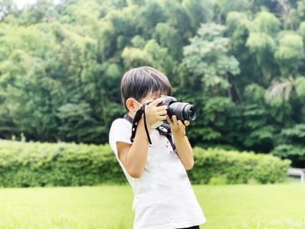 Child using a kids' camera to search for creatures in the park