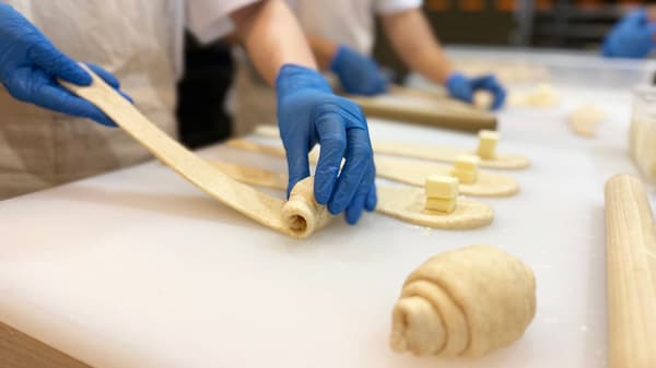 Roti sedang dibentuk dengan tangan di dalam toko