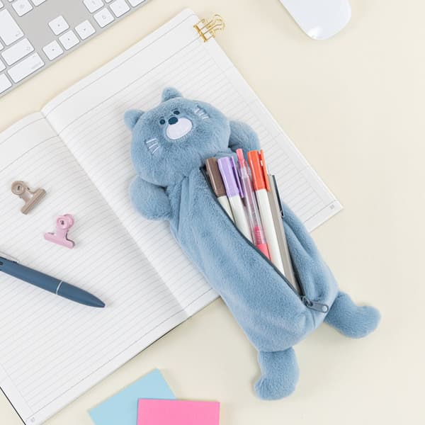 Estuche para lápices de gato sosteniendo bolígrafos, descansando sobre un cuaderno