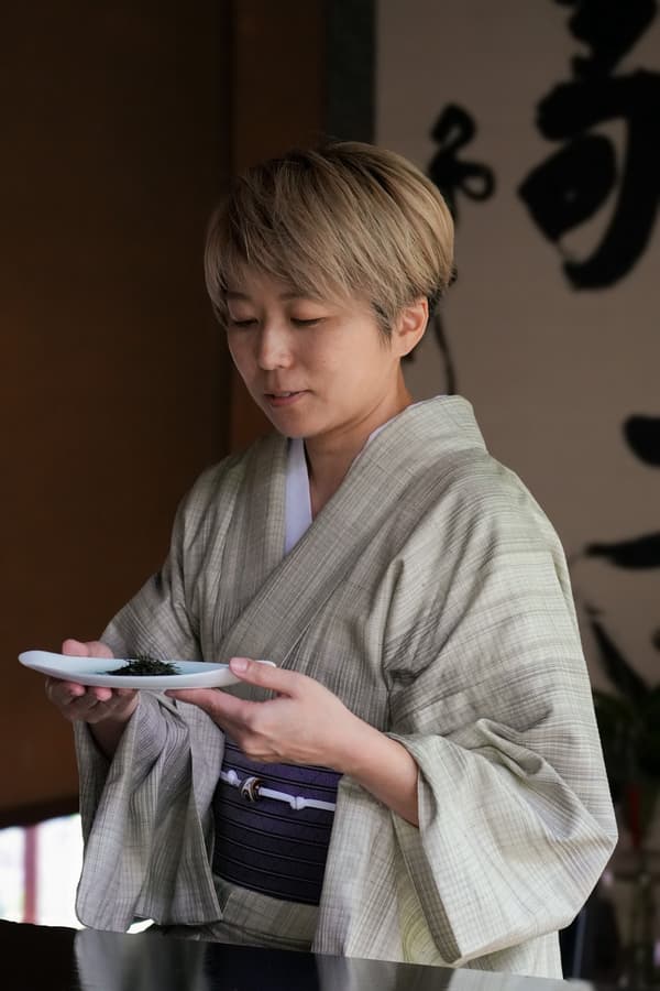 Tea brewing master holding a dish of tea leaves