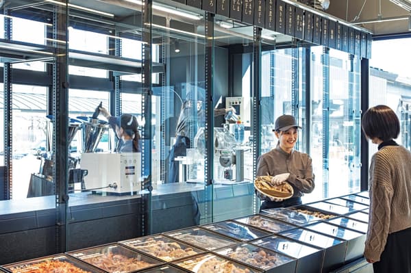 Un miembro del personal en el escaparate de ingredientes, donde los clientes eligen ingredientes secos para su mezcla de dashi personalizada
