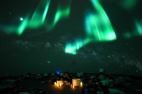 Participants lying down and feeling live sound healing amid aurora imagery
