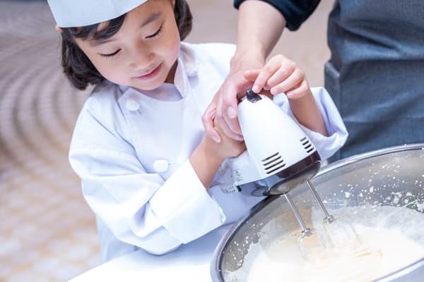 Young participants in chef's coats learning cake-making techniques