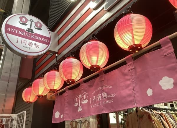 Storefront adorned with soft glowing lanterns and pink noren curtains