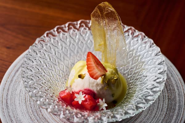Postre de fromage con fresas en un cuenco de cristal, cubierto con una fina tuile