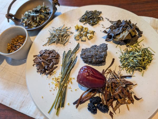 Assorted dried tea leaves and herbs arranged on a plate