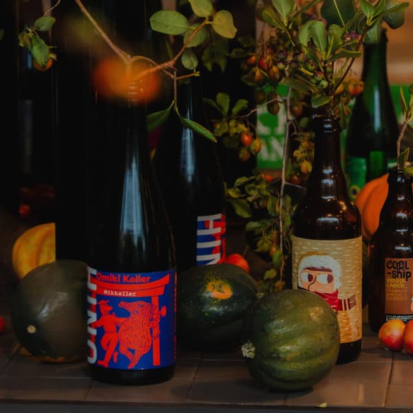 가을 과일 및 나뭇가지와 함께 전시된 Mikkeller 병