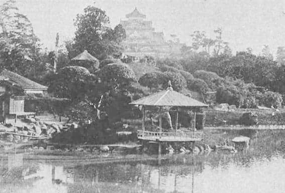 A historic photograph of a garden pond and pavilion with a castle keep in the background
