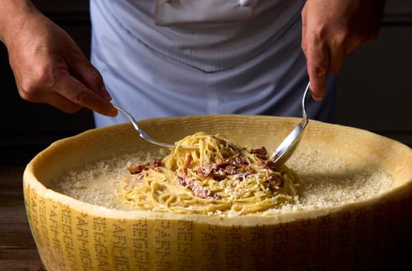 Espaguetis a la carbonara en rueda de queso, servidos frescos en la estación de cocina