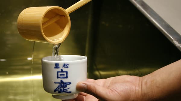 Sake yang dituangkan ke dalam cangkir bertanda Kuromatsu Hakushika