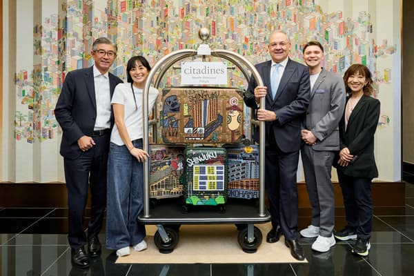 Para pembicara pada upacara pembukaan berdiri bersama koper-koper yang telah dilukis di Citadines North Shinjuku Tokyo