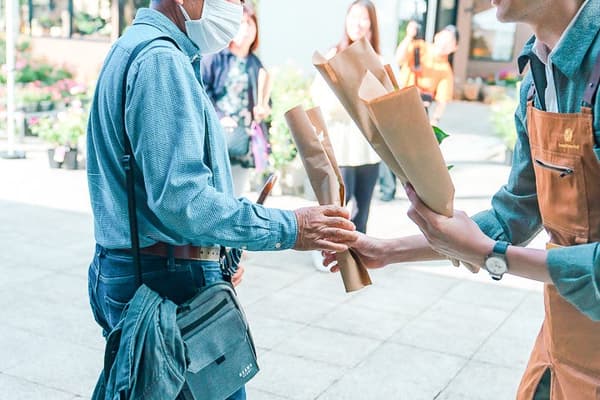 Staff hand a wrapped Maebashi-grown rose to a visitor at the giveaway