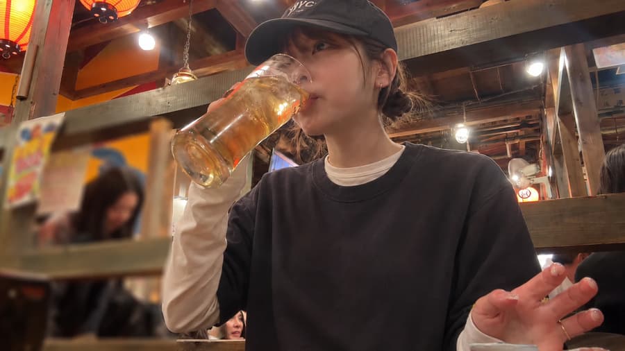 Mika sipping a big mug of beer under the lanterns at a lively izakaya