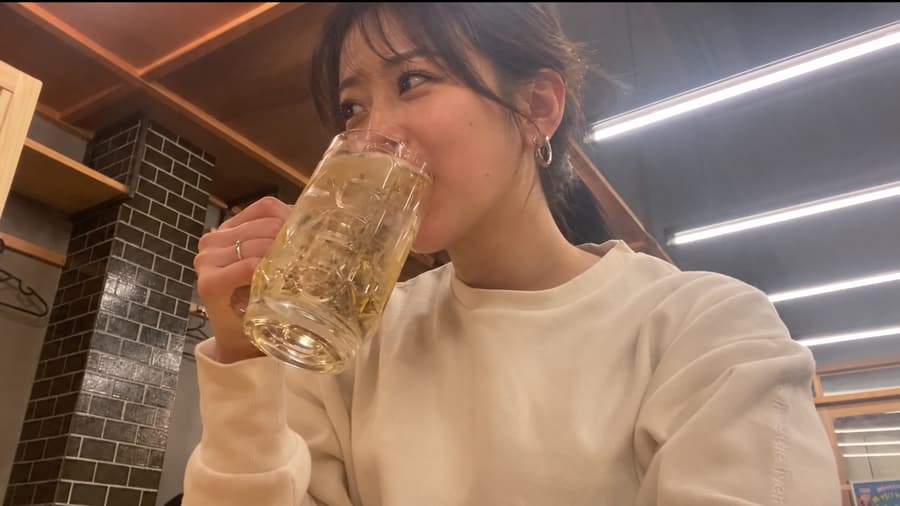 Aya sipping a highball from a large glass mug at a casual izakaya