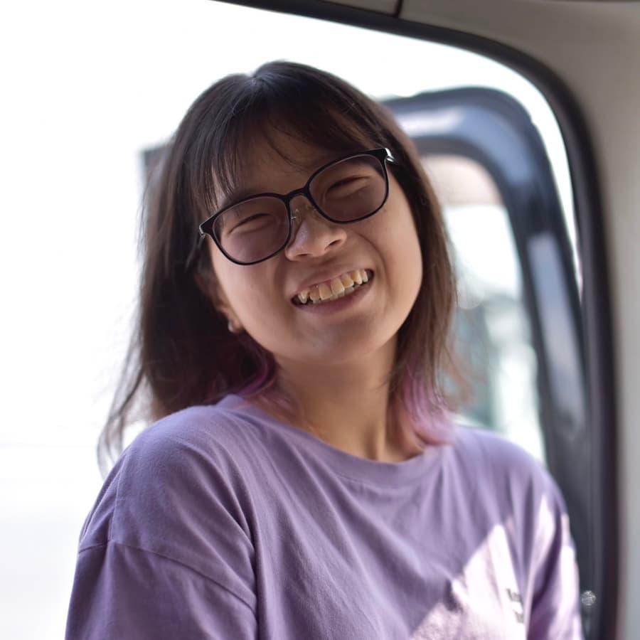 Lina laughing with eyes closed, leaning against the open door of a van